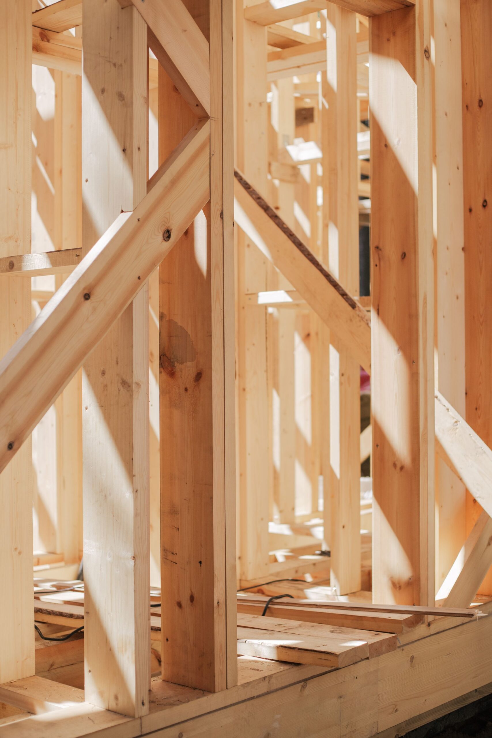 Wooden stud framing under construction, lit by daylight.